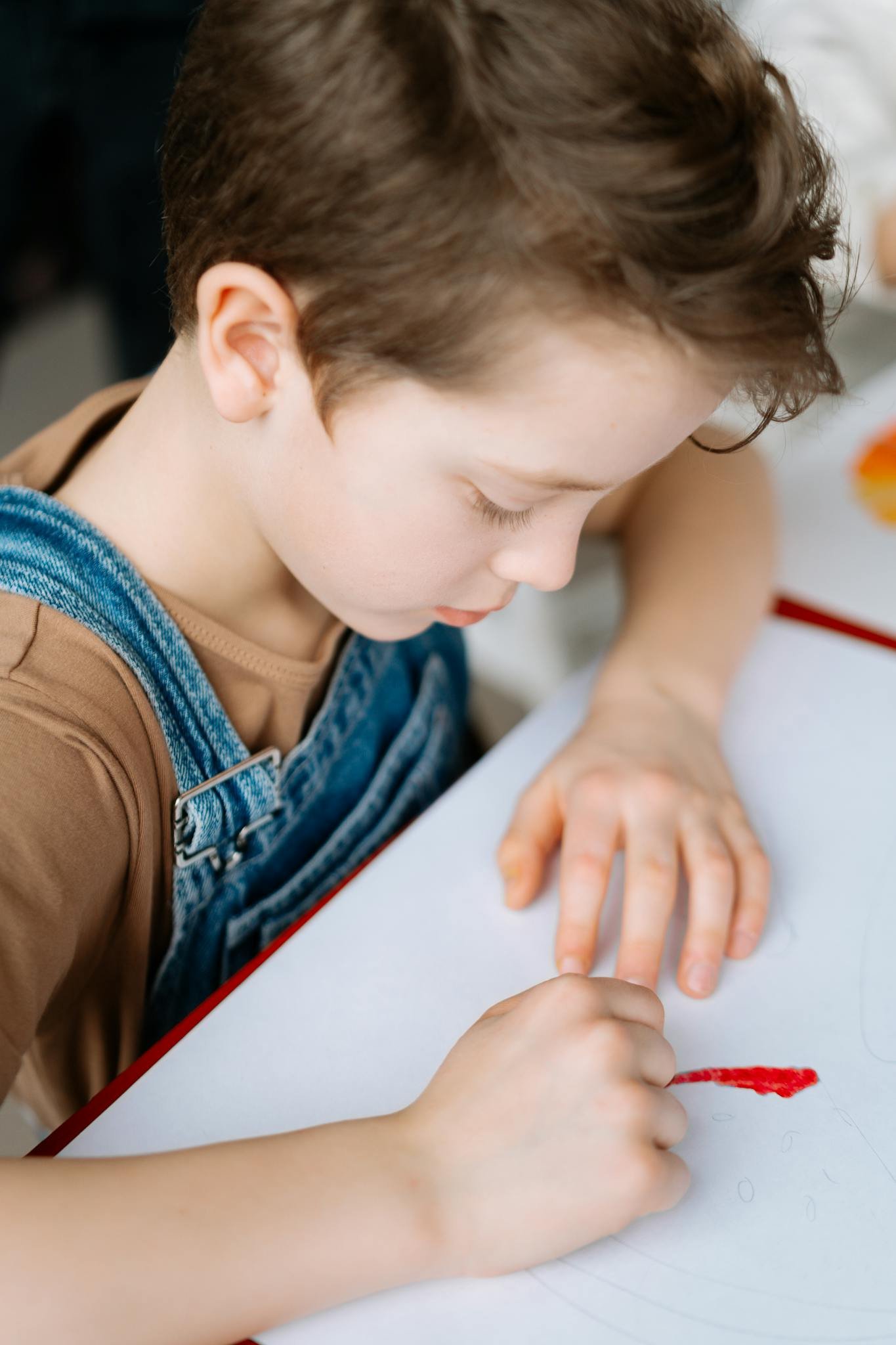 Young child engrossed in drawing, showcasing creativity in a casual indoor setting.